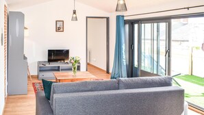 Una sala de estar moderna con un sofá gris, un televisor de pantalla plana y una mesa de centro de madera.