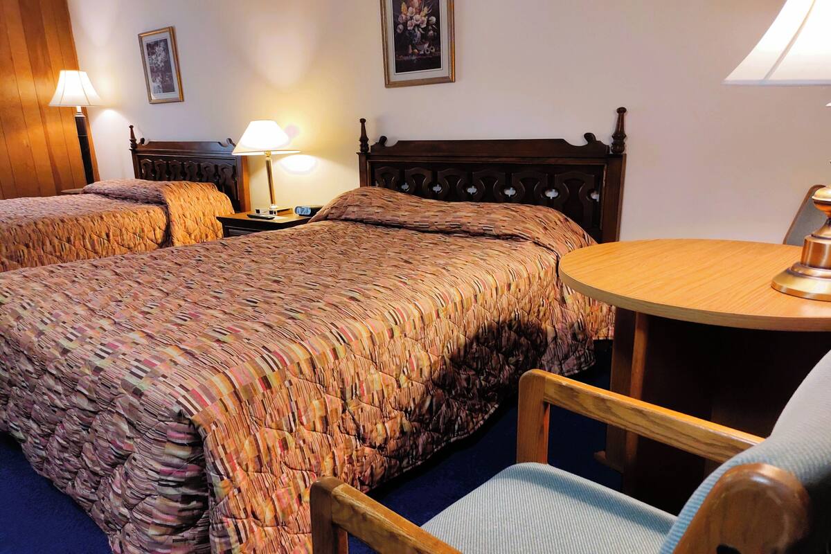 Ein Hotelzimmer mit einem großen Bett, zwei Nachttischen mit Lampen, einem runden Holztisch und einem Sessel.