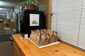 A reception desk with a sign, a potted plant, and a row of brown paper bags with 'Thank you' stickers. - Love Hotels Voyageur by OYO at International Falls MN (International Falls)