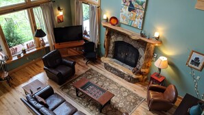 Una sala de estar acogedora con chimenea, sofás de cuero, una mesa de centro y un televisor.