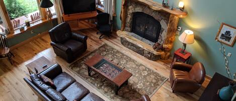 A cozy living room with a fireplace, leather sofas, a coffee table, and a television.