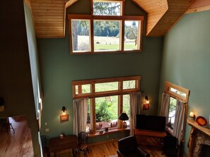A cozy living room with a large TV, wooden furniture, and a fireplace. - Gorgeous five bedroom home sleeps up to 13 guests. Extensive decks wrap the home, fishing pond, 11 acres with forest, pasture, and abuindance of wildlife. (Ashford)