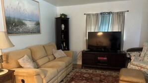 A living room with a sofa, a television, a cabinet, and a rug.