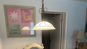 A dining table with a white tablecloth, a candle holder, and a placemat. There is a hanging light fixture above the table.