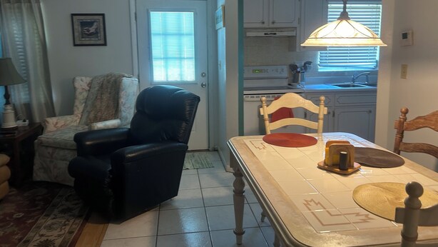 A dining area with a table, chairs, and a hanging light fixture.