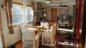 Une cuisine avec un coin repas, comprenant une table et des chaises, un ventilateur de plafond et un lave-linge.
