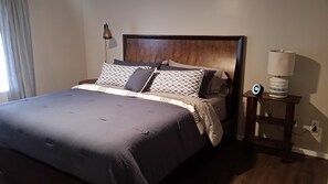 Relax in a spacious room with a large bed, wooden headboard, and bedside table.