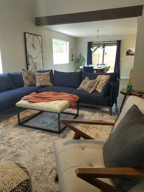 Relax in this stylish living room with a large sofa, ottoman, and dining area.