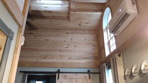 Una habitación con techo de madera, una puerta corredera de estilo rústico y un equipo de aire acondicionado.
