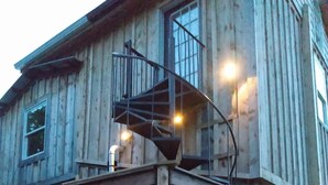 Un edificio de madera con terraza de madera y escalera en espiral.