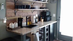 Una cocina con vigas de madera, un mueble estante empotrado, un lavamanos y un reloj en la pared.