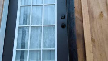 A wooden door with a white-framed window and a black door handle.