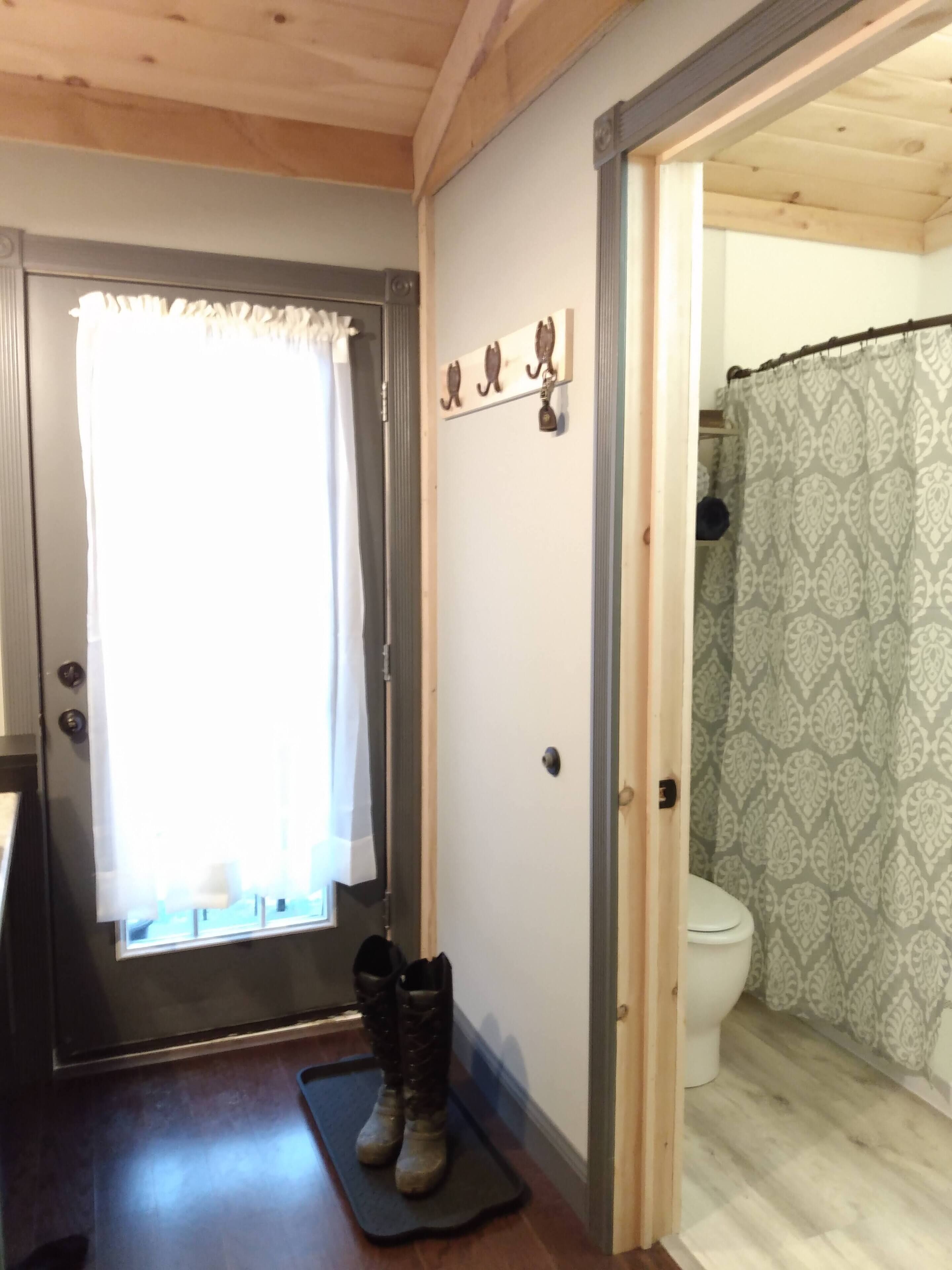 Un baño con inodoro, cortina de ducha y una puerta con perchero.
