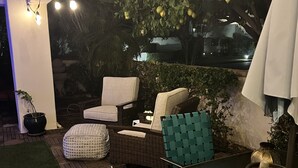 Un espace extérieur aménagé en terrasse, avec des meubles en osier, une table et des guirlandes lumineuses.