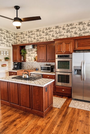 A kitchen with wooden cabinets, a stainless steel refrigerator, a microwave, an oven, and a gas stove. - The Manor 1885 Altamont (Altamont)