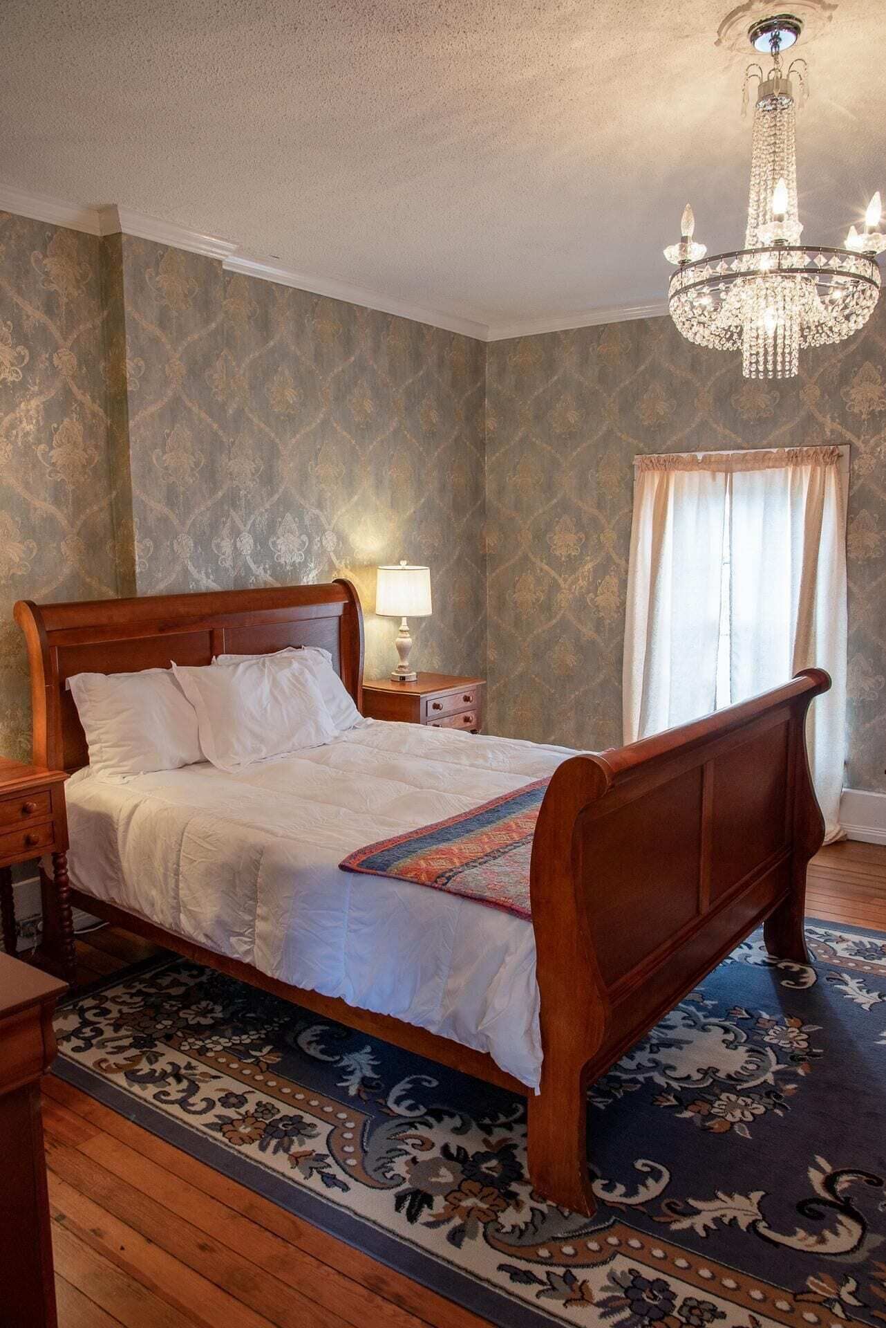 Ein klassisches Himmelbett mit Holzrahmen, weißer Bettwäsche und einer farbenfrohen Tagesdecke.