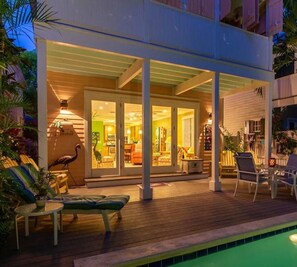 Une maison moderne dotée d’un patio couvert, d’une piscine et de mobilier d’extérieur.