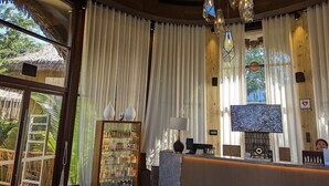 Un espace d’accueil comprenant un comptoir de réception en bois, un téléviseur et un présentoir de produits de toilette.