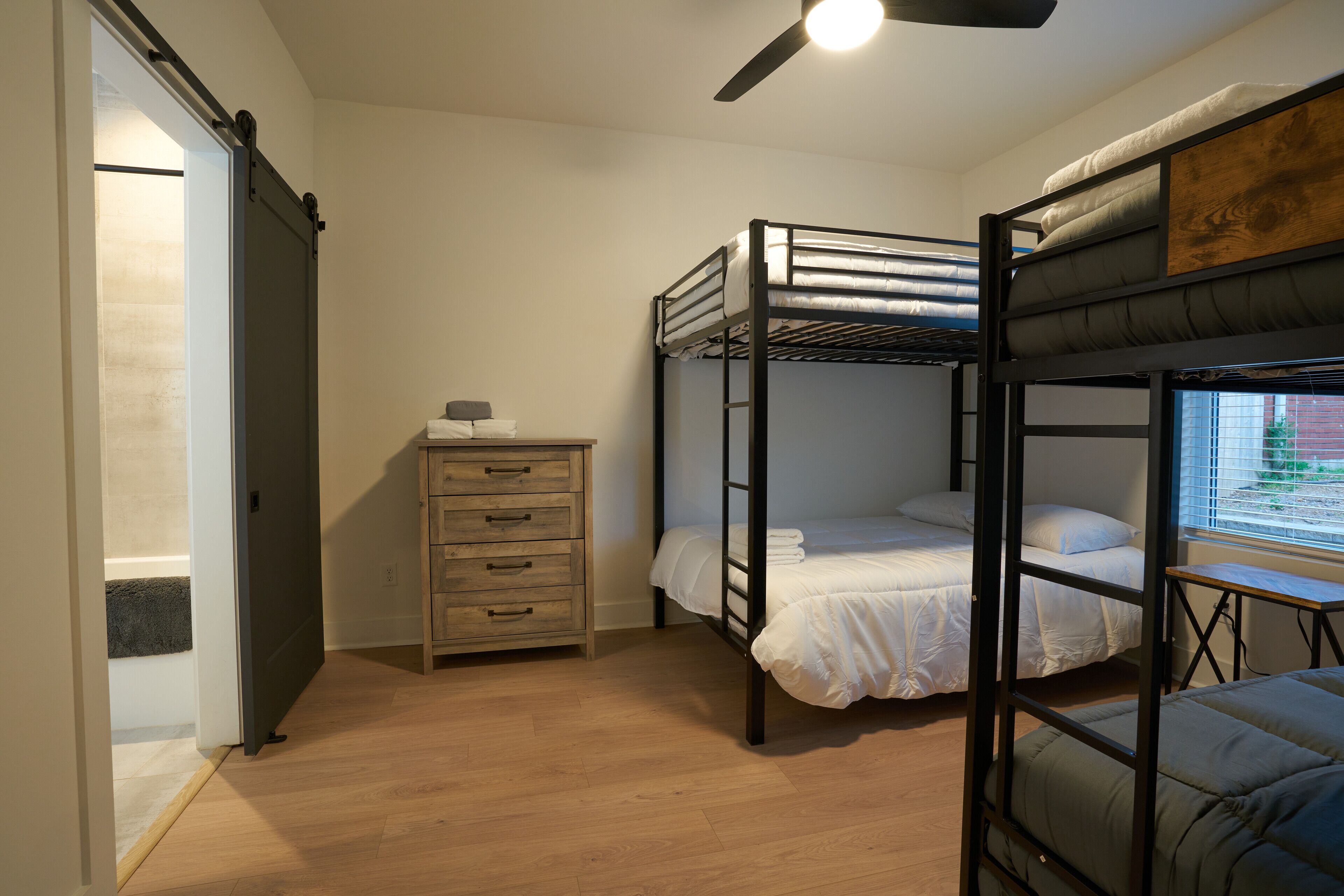 A bunk bed room with a wooden dresser and a ceiling fan.
