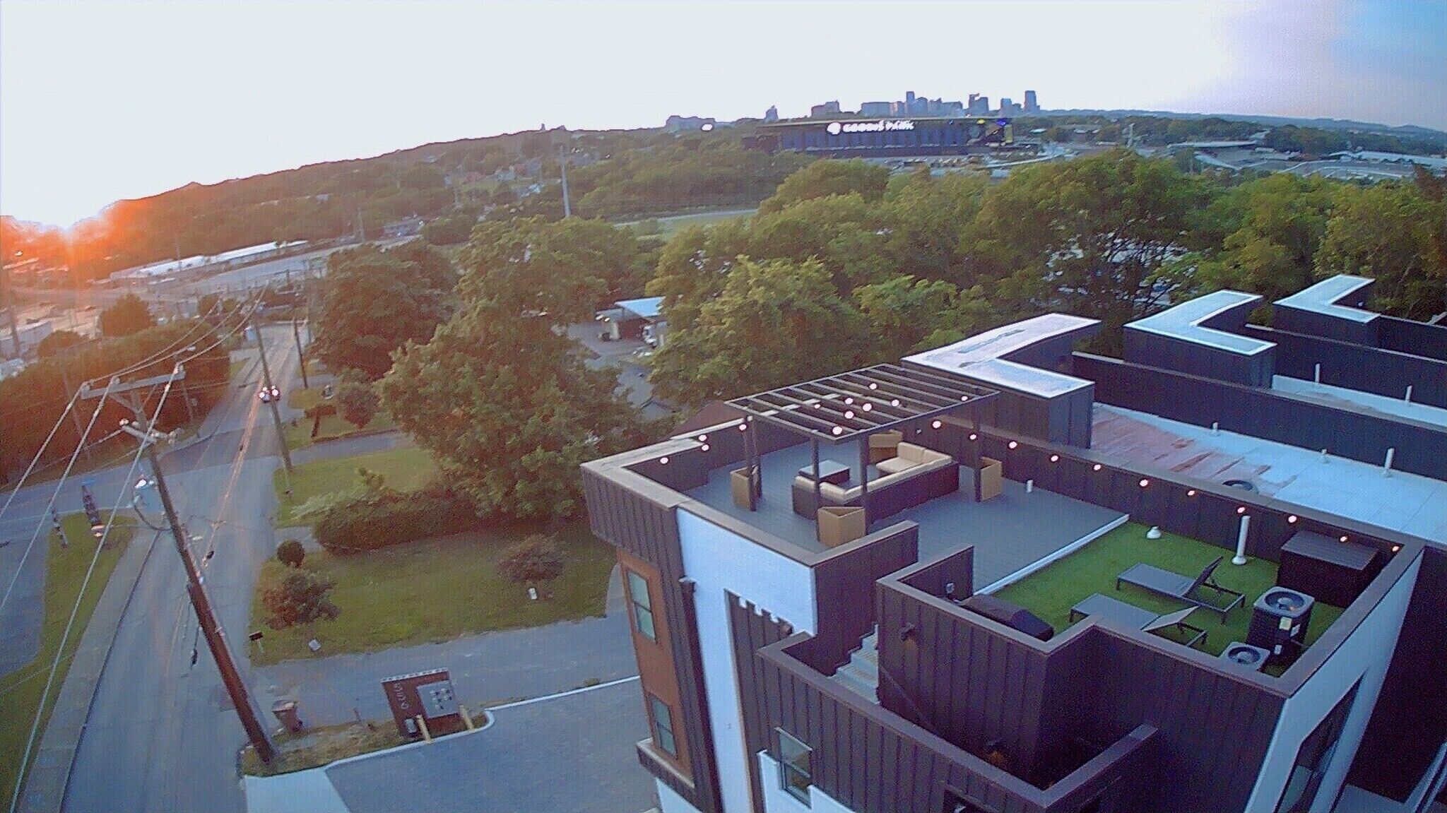 Een modern gebouw met een dakterras, buitenmeubilair en uitzicht op de omgeving.