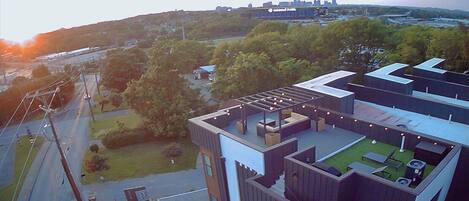 Een modern gebouw met een dakterras, buitenmeubilair en uitzicht op de omgeving.