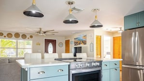 Een keuken met een centraal eiland, roestvrijstalen apparatuur en hanglampen.