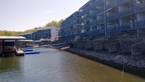 Un edificio de varios pisos con balcones, un muelle con barcos y un río.