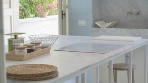 A kitchen with a marble countertop, a wire basket, jars, and a cutting board.
