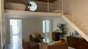 A spacious living area with a sofa set, a glass coffee table, and a staircase leading to an upper level.
