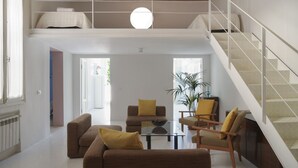 A spacious living area with a high ceiling, a staircase, and a view of the outdoors.