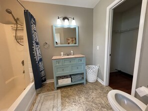 A bathroom with a shower, a sink with a mirror, a toilet, and a towel rack. - Spacious Oversized Townhome! The Blue Water Bungalow (Fort Walton Beach)