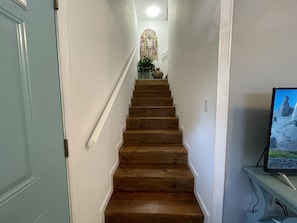 Una escalera de madera con paredes blancas y una planta pequeña en la parte superior.