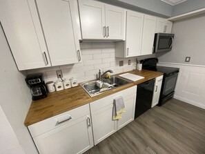 A modern kitchen with white cabinets, a wooden countertop, a sink, a coffee maker, and a microwave. - Spacious Oversized Townhome! The Blue Water Bungalow (Fort Walton Beach)