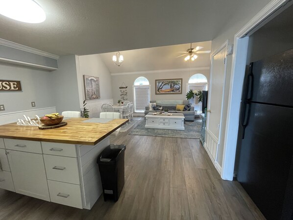 Una cocina moderna con una isla de madera, armarios blancos y un cubo de basura negro.