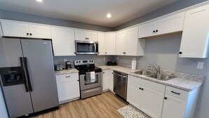 A modern kitchen with white cabinets, stainless steel appliances, a microwave, oven, dishwasher, and a granite countertop. - Completely remodeled downtown apartment!  2 large bedrooms! (Cascade)