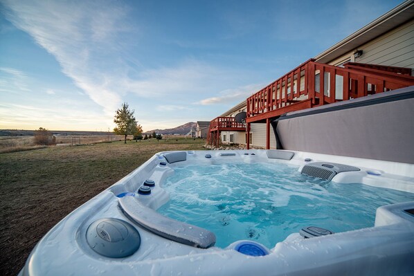 Un jacuzzi con muelle de madera y una casa al fondo.