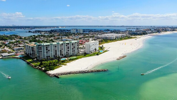 An aerial view of a coastal area with a beach, a marina, and high-rise buildings. - Poolside Updated Studio Across from the Beach!! (St. Pete Beach)