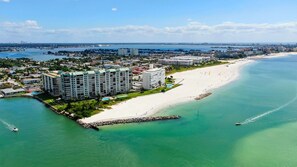 Luftaufnahme einer Küstenregion mit Strand, einer Marina und Hochhäusern.