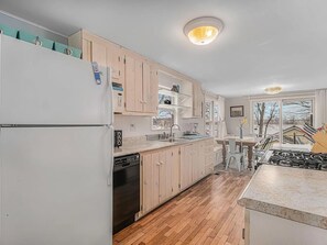 A kitchen with wooden cabinets, a refrigerator, a dishwasher, and a stove. - Country cottage, Baseline Lake . Come fish, kayak or enjoy a camp fire. (Gobles)