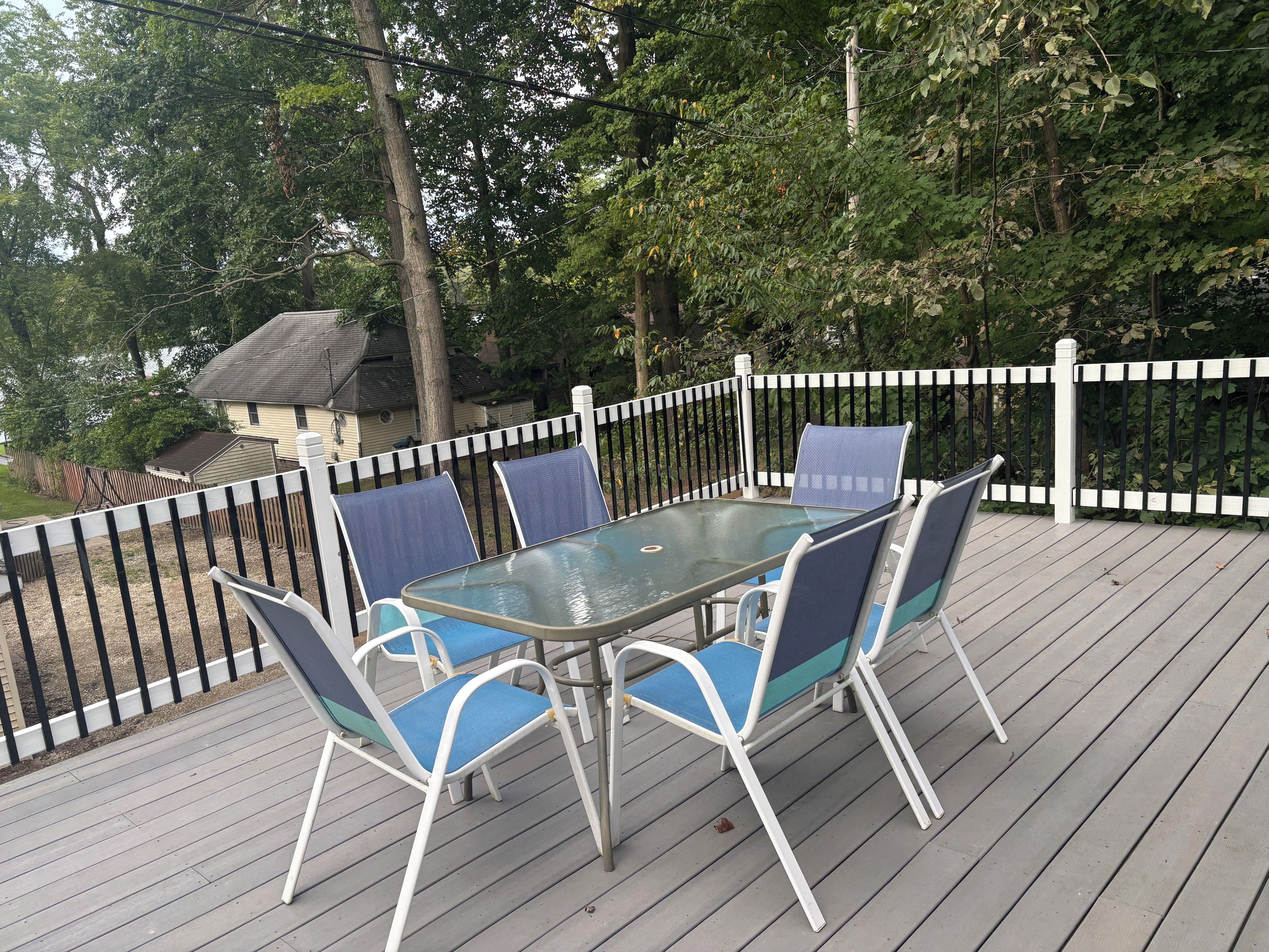 An outdoor deck with a table and chairs, surrounded by a white picket fence.