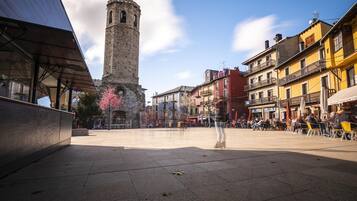 Una plaça amb una torre històrica, edificis moderns i zones d'aigües obertes.