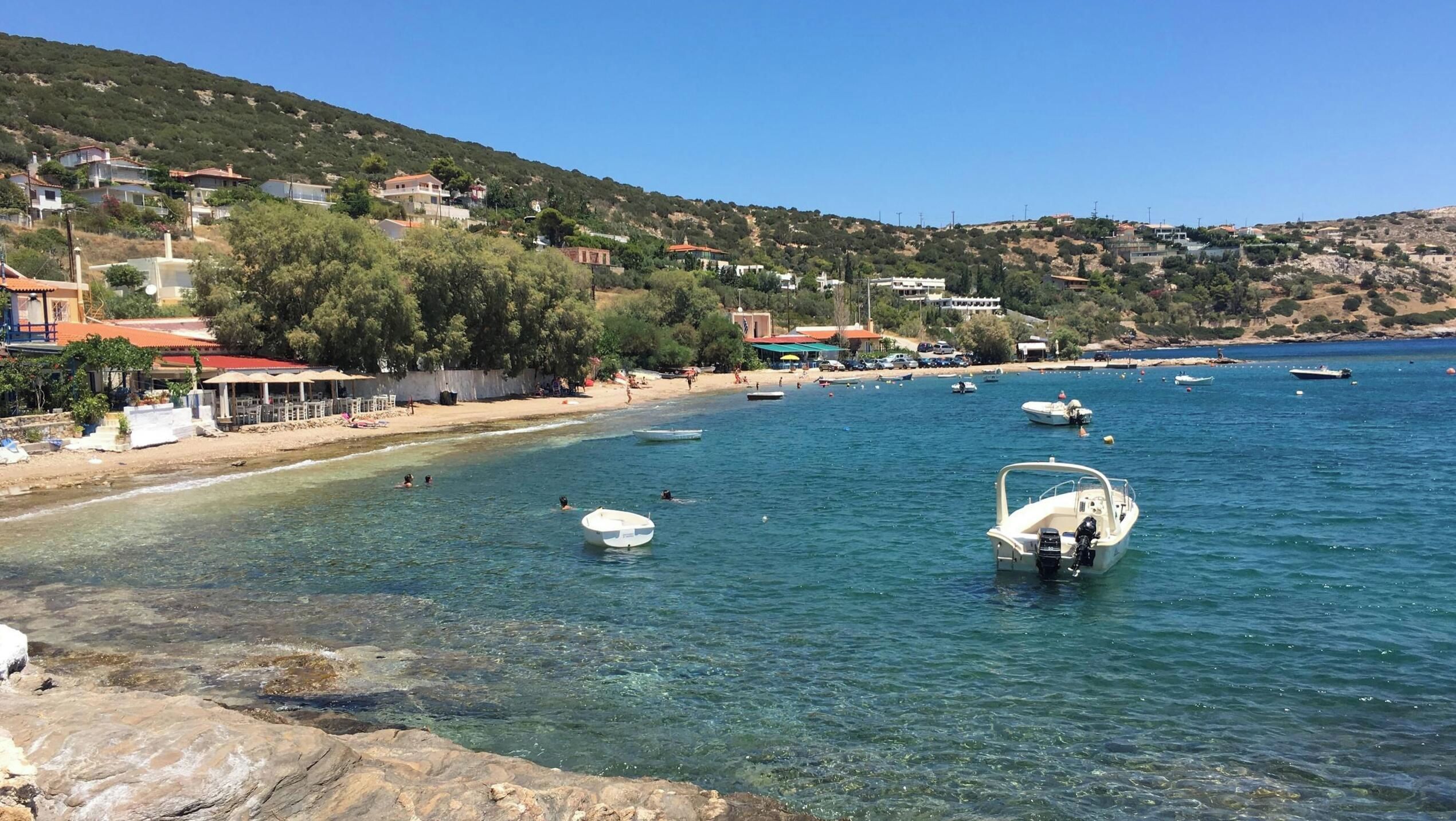 A coastal area with clear waters, boats, and buildings on the shore.