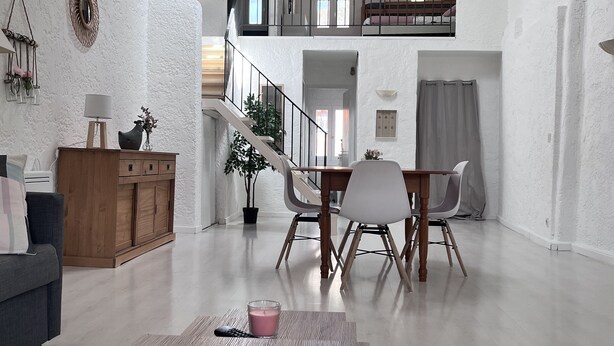 A spacious living area with a wooden dining table, a sofa, and a staircase leading to an upper level. - Apartment (Riez)