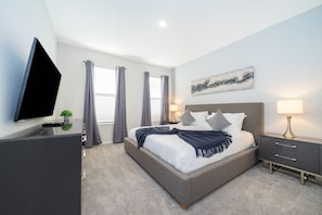 A modern bedroom with a large bed, bedside tables, a flat-screen TV, and a painting on the wall.