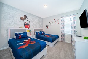 A bedroom with two beds, a desk, and a TV.