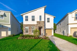 A modern two-story house with a stone facade, a front yard with a pathway, and a garage.