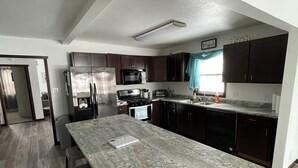 A modern kitchen with dark cabinets, a large granite countertop, and a central island with bar stools. - Lake view home on 1.3 acres, lake access 1 block away.
Camper parking available. (Spirit Lake)