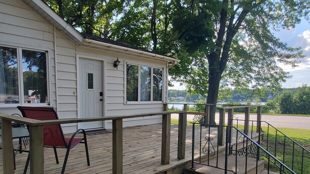 A wooden deck with a railing, a covered porch, and a view of a lake. - Lake view home on 1.3 acres, lake access 1 block away.
Camper parking available. (Spirit Lake)