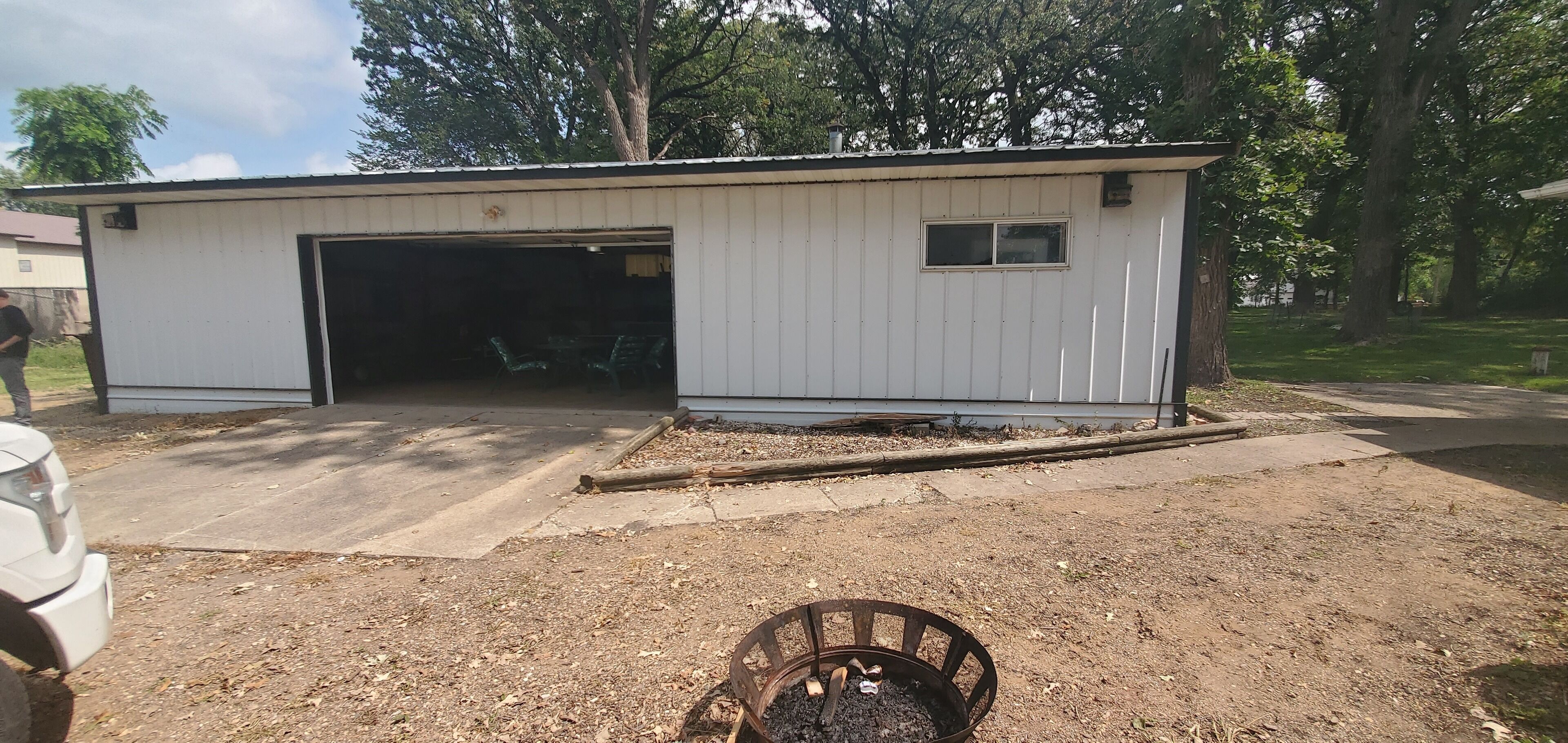 A small, single-story building with a garage door open, revealing a green lawn chair inside.