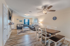A spacious living room with a dining area, wooden flooring, a ceiling fan, and a view of the outdoors. - Cozy 2bed/1.5bath beach townhome!! 75 steps to the beach! Stunning ocean view! (Port St. Joe)
